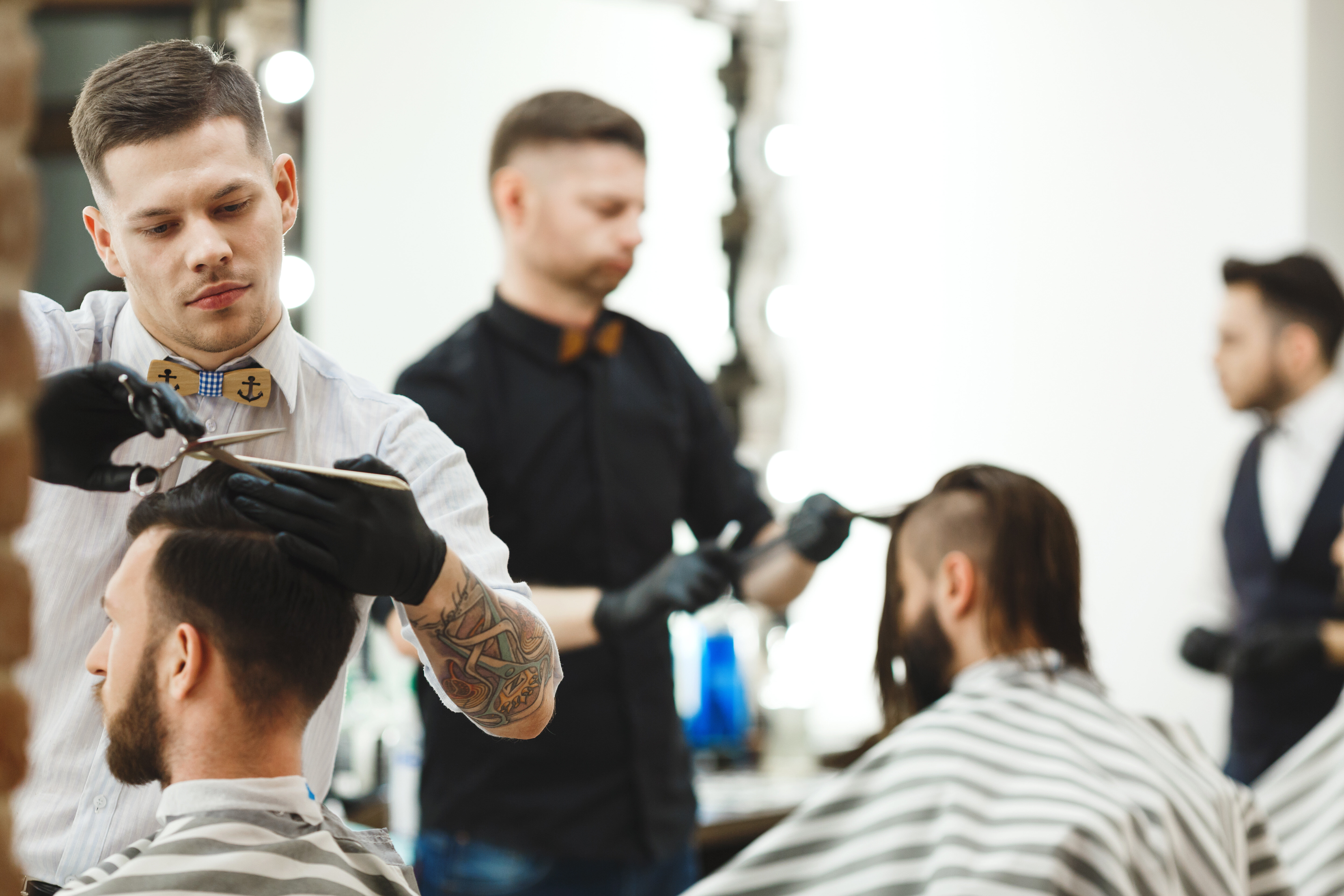 Two barbers doing haircuts for men in a men’s hair salon