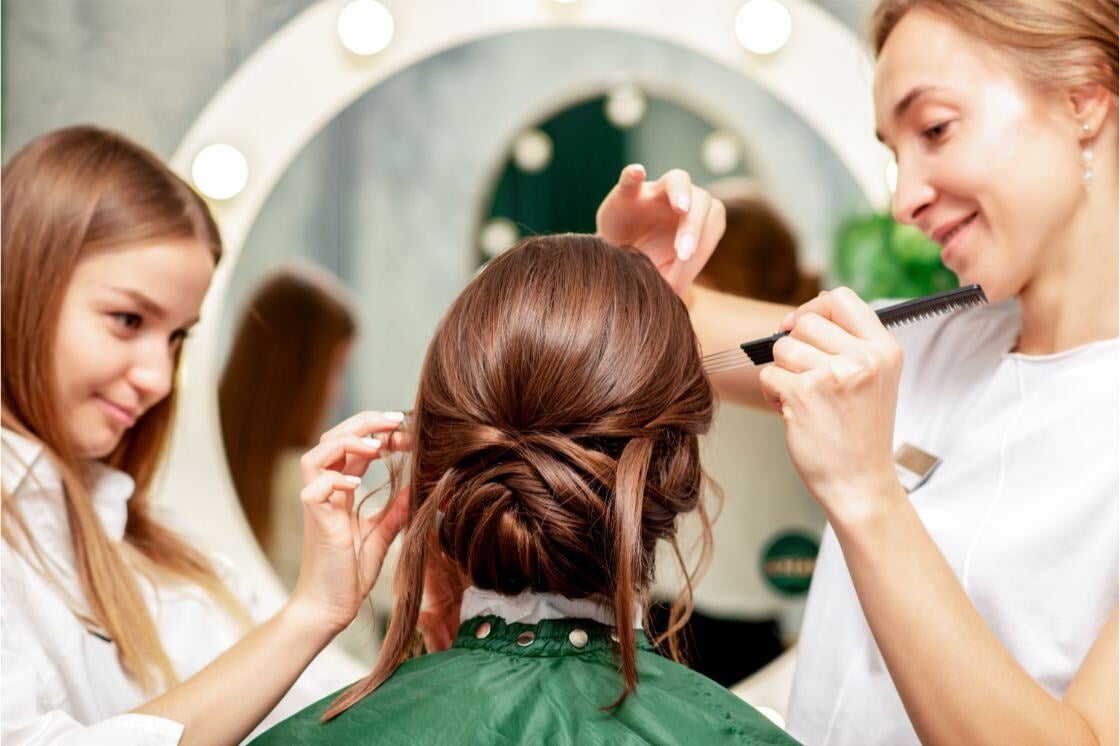 Two stylists take care of a client that sits in front of them